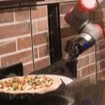 Un brazo robot prepara una pizza
